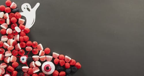 Multiple halloween candies and ghost toy with copy space on grey background