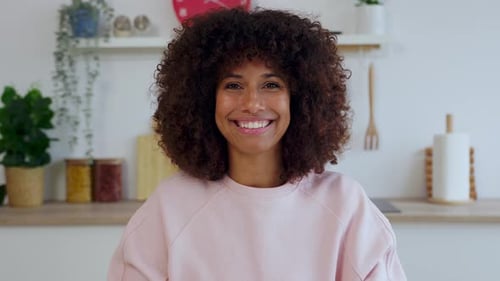 Portrait of Young Happy Woman Smiling at Camera Sitting in the Kitchen at Home