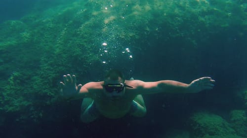 Homme aux bras grands ouverts faisant de la plongée en apnée et nageant sous l'eau avec masque de plongée en voiture turquoise