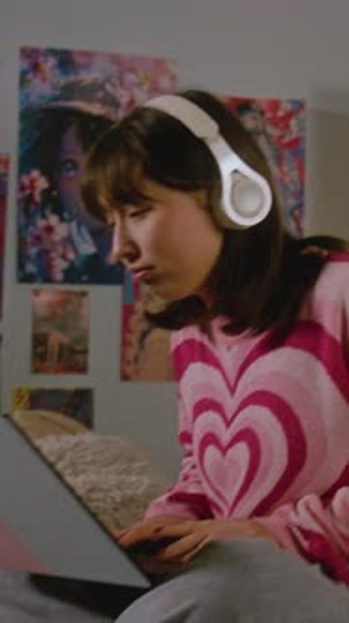 Teen Girl in Headphones Chats on Laptop in Her Cozy Bedroom