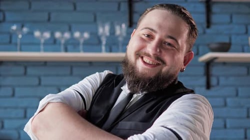 Cheerful Authentic Handsome Bartender Poses for the Camera in Bar