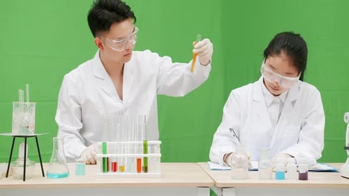 Portrait scientist with protective glasses examining lab tube with green fluid. Microbiology science