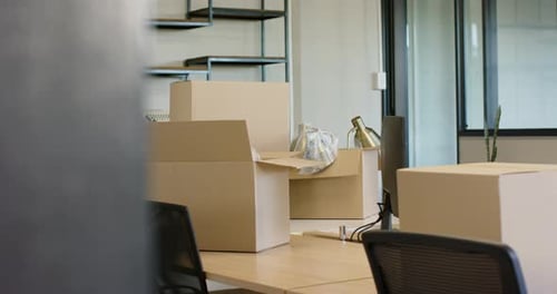L'obstacle qui s'éloigne révèle une boîte en carton ouverte sur le bureau central, montrant l'emballage à déménager