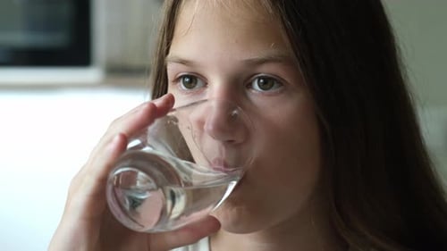 Kid Girl Drinking Clean Transparent Water From Glass at Home Close Up