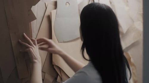 Seamstress Takes Patterns From Rack While Working