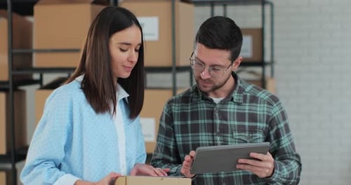 A Man Sales Manager Using a Tablet Computer is Talking to an Employee Holding a Cardboard Box