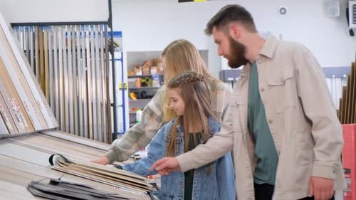 A Young Family in a Hardware Store Chooses a Wooden Laminate Surface for Home Renovation