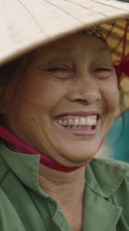 Portrait of a Mature Female Farmer Wearing a Headscarf and a Large Wicker Hat in Vietnam
