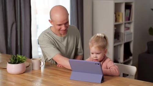 A Child with Cochlear Implants Plays with a Tablet Computer with His Father