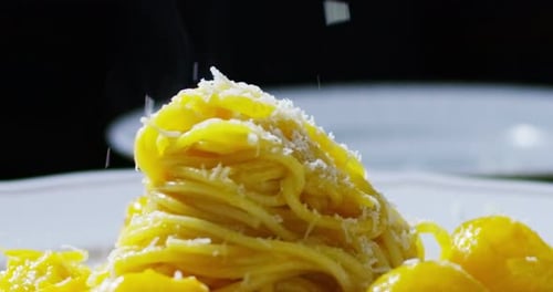 Cheese is Sprinkled onto a Plate of Pasta