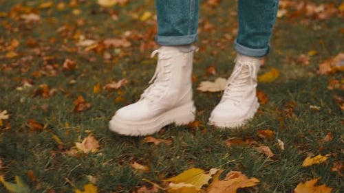 Woman in Boots Walking Through Autumn Leaves