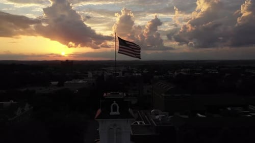 Drone circles a tower with an American flag at sunset