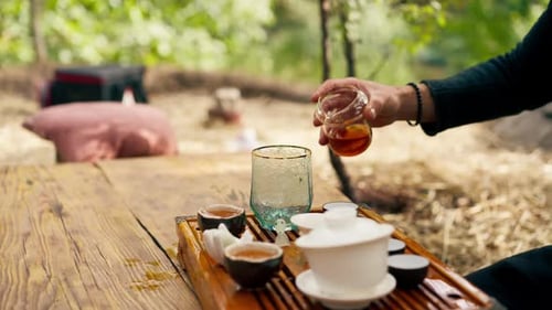 close-up The hands of a professional tea master who pours fresh natural green tea from a teapot