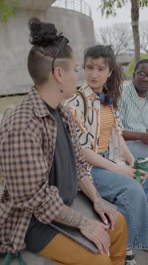 Girl Talking to College Friends on Bench Outdoors in the Park