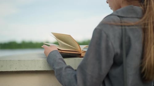 Woman Reading Book on Bridge Overlooking Water