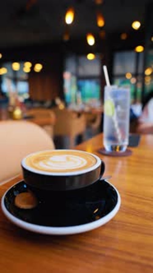 A Delightful Scene Featuring Coffee and Water Placed on a Table Amidst a Stylish Modern Cafe