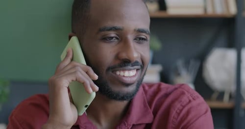 Smiling Young Adult Talking on Cellphone Indoors