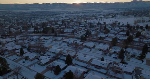 Drone shot of the sun setting over the Rocky Mountains in Denver, CO on a snowy winter day.