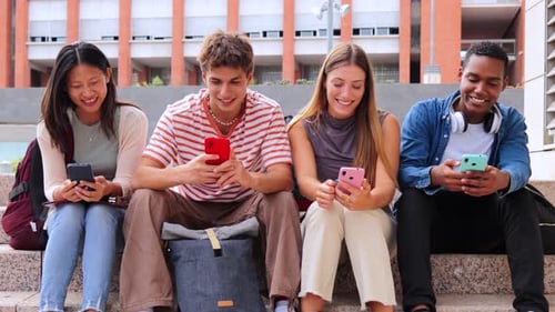 Grupo de estudiantes de secundaria multirraciales que se divierten viendo una Aplicación de Redes Sociales en un teléfono inteligente en