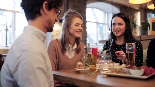 Happy friends enjoying food drinks and holiday cheers at a restaurant