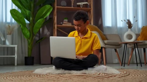 Boy Using Laptop while Sitting Cross Legged Indoors
