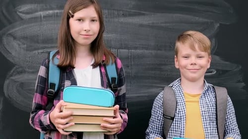 Two Happy Kids on First School Day on Blackboard Background Cute Clever Boy and Teen Girl with