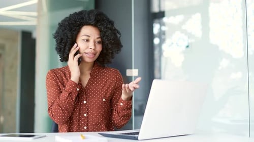 Woman Works on Laptop and Talks on Phone