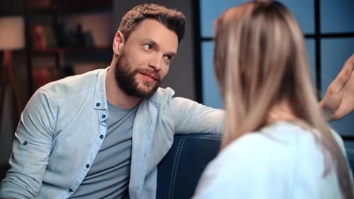 Man and Woman Talking on a Couch Indoors