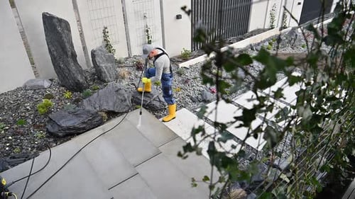 Man Pressure Washing Stone Patio in Modern Garden