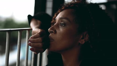 One sad pensive black middle-aged woman gazing at view from balcony in deep melancholic