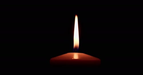 Eine einzelne große gelbe Kerzenflamme leuchtet und erlischt, isoliert auf schwarzem Hintergrund. Zeitlupe und