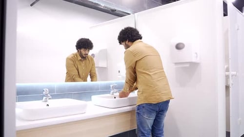 Young Adult Washing Hands in Public Restroom