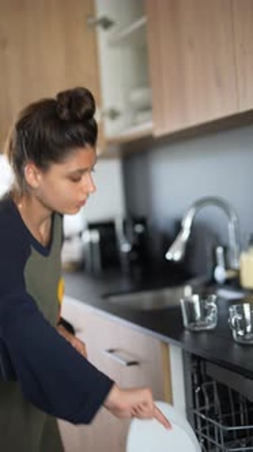 A Woman is Organizing Her Kitchen Loading the Dishwasher and Tidying Up Her Home