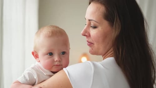 Woman Holding Baby Close Indoors by Window