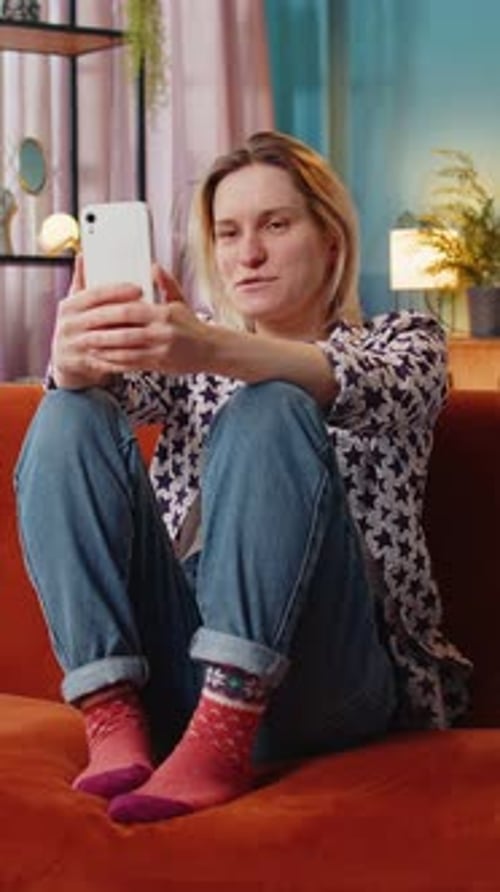 Woman Relaxing on Sofa Video Calling on Phone