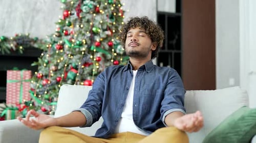 Man Meditating in Front of Christmas Tree
