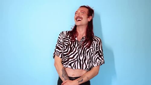 Non-binary person laughing on blue background