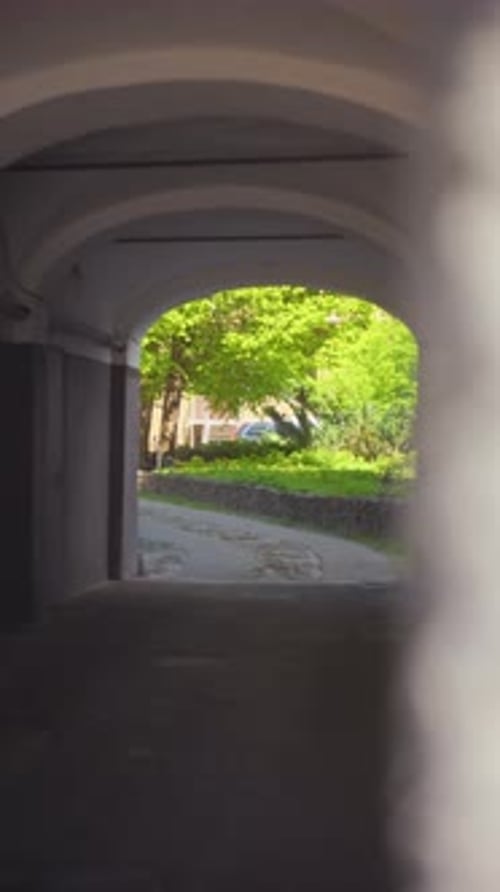 A Tranquil Pathway Meanders Through an Arched Entrance That is Surrounded By Lush Greenery and