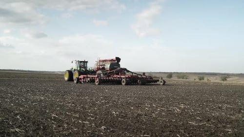Green tractor seeding wheat on the field