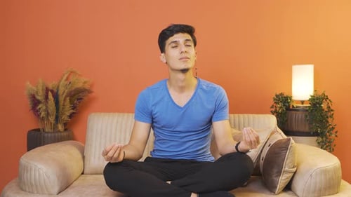 Young Man Sitting on Couch Meditating Peacefully