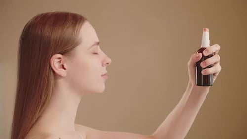 Closeup Side View of a Young Caucasian Woman Spraying Face Water with a Mist