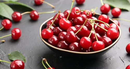 Ripe cherries and leaves on black table, closeup