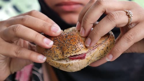 Hand Holding Beef Burger on Table Close Up