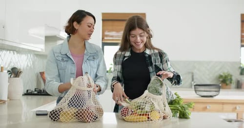 Diversas amigas después de las compras desempacando bolsas de malla en la cocina comprobando la frescura de la col rizada en bolsas