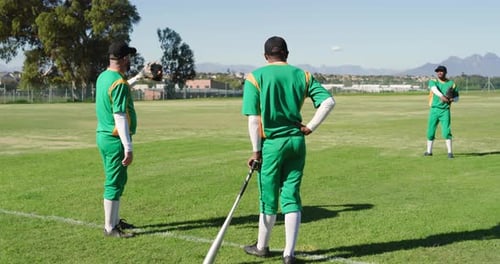 Male baseball teammates warming on field with outfield player tossing ball and catching with gloves