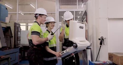 Male technician guiding female trainee operating CNC machine controller during smart factory