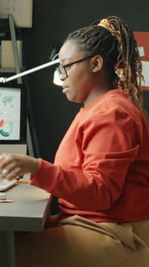 Woman Working at Computer and Taking Notes Indoors