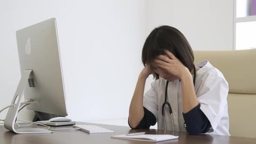Stressed Female Doctor Suffers From Headache While Being Overworked in Clinic