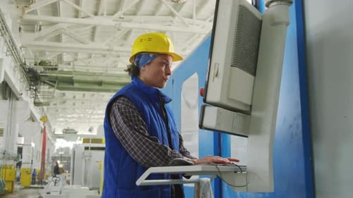 Fabriktechnikerin, die Industriemaschine mit Computer bedient