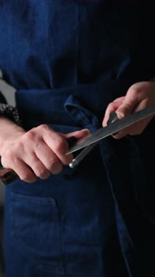Girl In Apron Sharpening A Big Knife With Honing Rod Tool